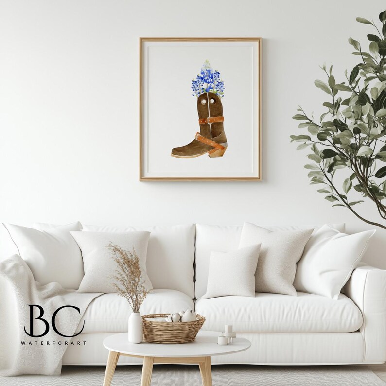 Puede incluir: Una pintura de acuarela de una bota vaquera marr&oacute;n con flores azules en la parte superior. La bota est&aacute; sobre un fondo blanco.