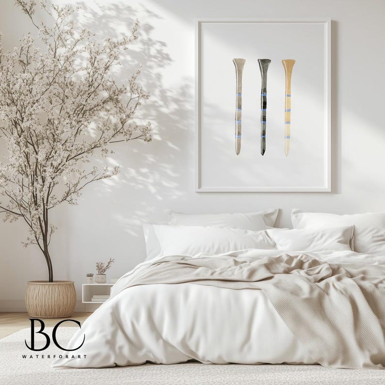 May include: A framed watercolor painting of three golf tees in different colors. The tees are arranged vertically in a row. The background is white.
