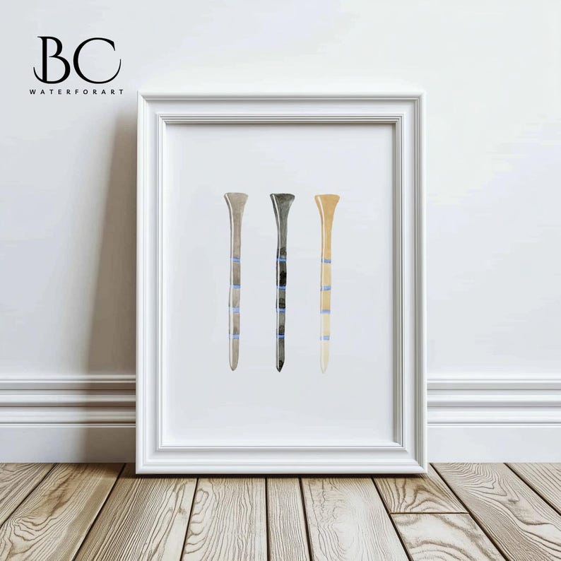 May include: A framed watercolor painting of three golf tees in different colors: beige, gray, and brown. The tees have blue stripes.