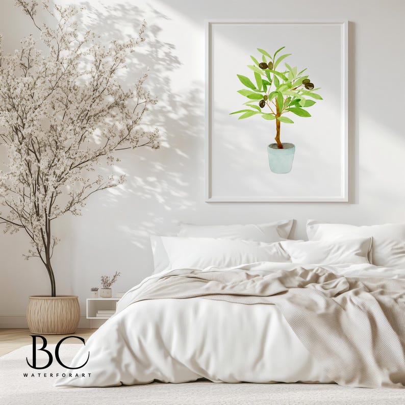 May include: A watercolour painting of a potted olive tree with green leaves and black olives. The painting is framed in a white frame and is hanging on a white wall above a white bed with a beige blanket.