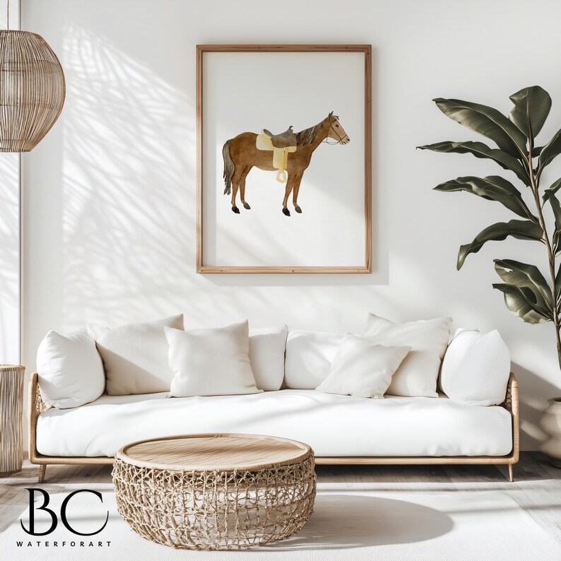 May include: A watercolor painting of a brown horse with a saddle on its back. The horse is standing on a white background. The painting is framed in a light wood frame and is hanging on a white wall.