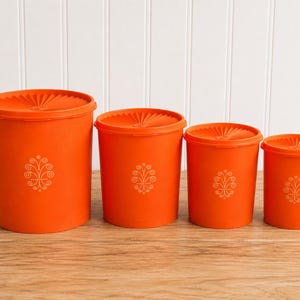 Set di barattoli Tupperware arancioni vintage: 4 coperchi a raggiera, contenitori da cucina in stile metà secolo.