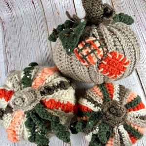 May include: Three handmade crochet pumpkins in shades of gray, orange, green, and cream. The pumpkins have detailed stems, leaves, and decorative patches. These fall-themed decorations are perfect for adding a touch of autumn to any home.