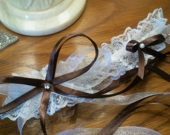 Jolie jarretière en dentelle blanche garnie de nœuds en ruban de satin marron et d'organza de couleur blanc