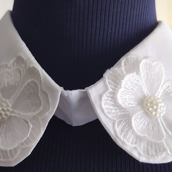 Faux col Claudine en coton de couleur blanc, décoré d'une fleur guipure de couleur blanche et perlée.