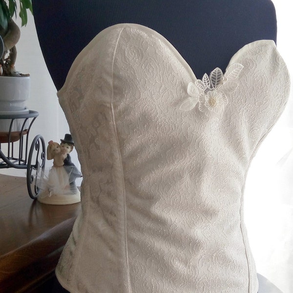 Joli corset en tissu brocart formes fleurs satinées de couleur blanc cassé / écru