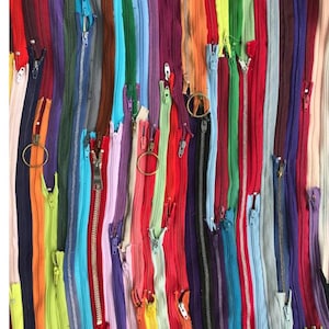May include: A vibrant display of colorful zippers in various shades, including red, blue, green, and purple. The zippers are arranged vertically, creating a textured and visually appealing pattern. Some zippers are open, while others are closed, showcasing the variety.