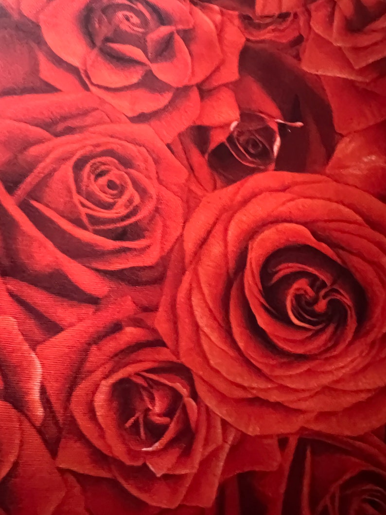 May include: Close-up of a fabric with a pattern of red roses. The roses are in various stages of bloom, with tightly furled buds and fully opened blossoms. The color palette is dominated by shades of red, with darker tones in the center of the roses.