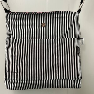 K&ouml;nnte beinhalten: Schwarze und wei&szlig;e gestreifte Tragetasche mit einem einzigen Druckknopfverschluss und einem kleinen Etikett mit der Aufschrift "Homespun".