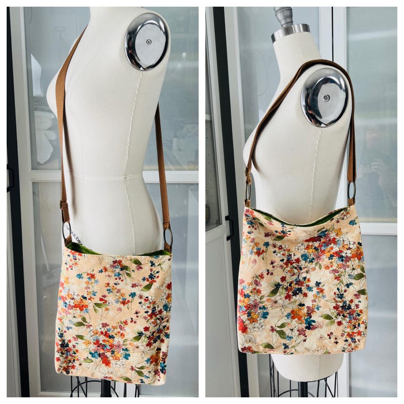 Puede incluir: Un bolso bandolera beige con estampado floral y correa de cuero marr&oacute;n. El bolso tiene un forro verde.