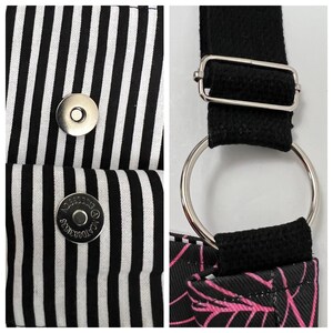 K&ouml;nnte beinhalten: Eine schwarze und wei&szlig;e gestreifte Stofftasche mit einem schwarzen Riemen und silbernen Beschl&auml;gen. Die Tasche hat zwei silberne Druckkn&ouml;pfe und ein schwarzes Stofffutter.