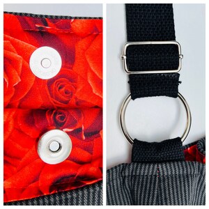 May include: Close-up of a tote bag with a red rose pattern lining and a magnetic snap closure. The bag features a black strap with a silver metal ring and buckle. The exterior fabric has a gray and black pinstripe design.