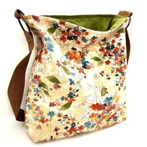 Puede incluir: Un bolso bandolera beige con estampado floral, correa marr&oacute;n y forro verde.
