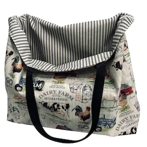 May include: Cream-colored tote bag with a farm-themed print featuring cows, chickens, and the text "Dairy Farm Artisan Produce." The bag has black handles and a striped interior. The bag is open, showing the interior lining.