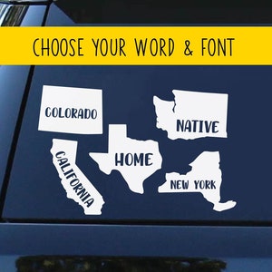 May include: A black car with a white decal on the back window. The decal features outlines of the states of Colorado, California, Texas, New York, and Washington. The words "Colorado", "California", "Home", "Native", and "New York" are written on the decal.