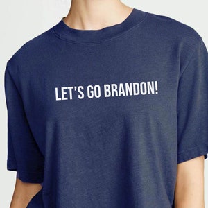 May include: A navy blue cropped t-shirt with the text "LET'S GO BRANDON!" printed in white.