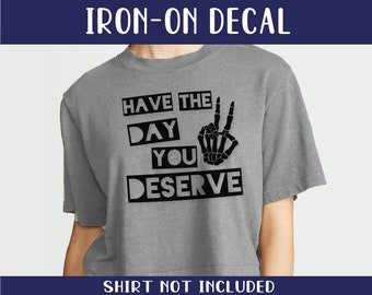 May include: Iron-on decal featuring a skeleton hand making a peace sign with the text "Have the day you deserve".