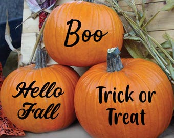 May include: Three orange pumpkins stacked together, each with a dark green stem. The top pumpkin has the word "Boo" written on it. The bottom left pumpkin says "Hello Fall", and the bottom right pumpkin says "Trick or Treat".