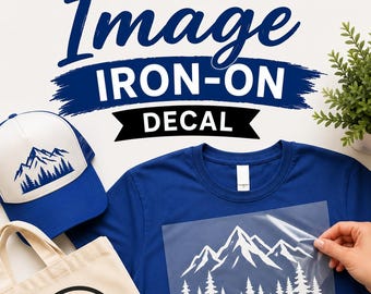 May include: A blue t-shirt, a white and blue trucker hat with a mountain graphic, a beige tote bag with a paw print, and a clear sheet with a white mountain and pine tree iron-on decal. The text reads CUSTOM Image IRON-ON DECAL.