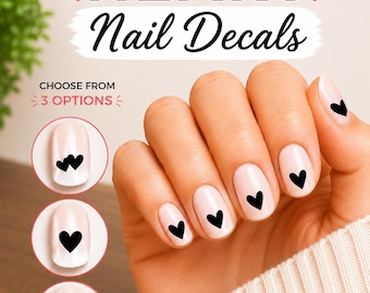 Pode incluir: Adesivos de unha com desenhos de corações pretos em unhas rosa claro. A imagem inclui o texto HEART Nail Decals e CHOOSE FROM 3 OPTIONS, com três inserções circulares mostrando diferentes estilos de posicionamento de corações nas unhas.