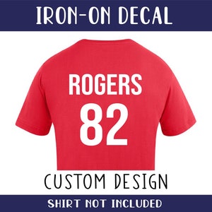 May include: Red iron-on decal featuring the name "ROGERS" and the number "82" in white. The decal is for a custom design and the shirt is not included.