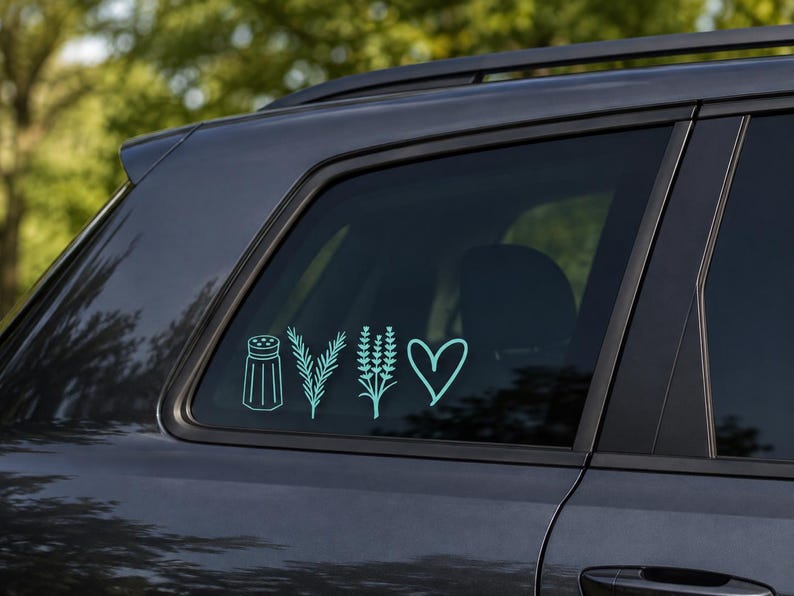 Op de afbeelding: Een lichtblauwe vinylsticker op een donkergrijze autoruit, met vier lijntekeningen: een zoutvaatje, een takje rozemarijn, een lavendeltak en een eenvoudige hartvorm, allemaal in een horizontale rij naast elkaar geplaatst.