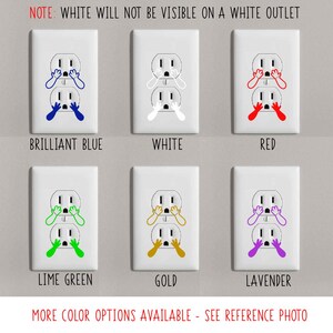 May include: A set of six outlet covers with a variety of colors, including brilliant blue, white, red, lime green, gold, and lavender. Each cover features a cartoon image of a face with its hands over its eyes, as if it is scared. The text "NOTE: WHITE WILL NOT BE VISIBLE ON A WHITE OUTLET" is at the top of the image. The text "MORE COLOR OPTIONS AVAILABLE - SEE REFERENCE PHOTO" is at the bottom of the image.