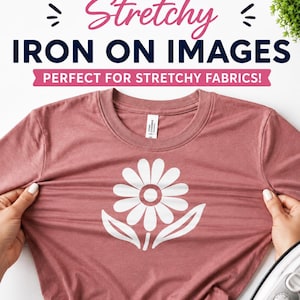 May include: A dusty rose t-shirt featuring a white daisy graphic on the chest. The text above reads Stretchy IRON ON IMAGES PERFECT FOR STRETCHY FABRICS! The fabric is being pulled horizontally to demonstrate elasticity near a white iron.