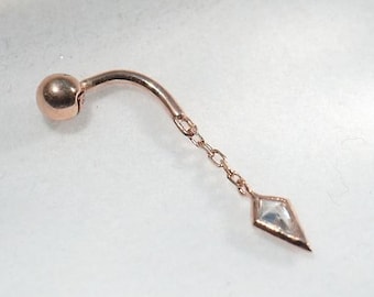 May include: A rose gold body jewelry piece with a small ball at the top and a dangling diamond-shaped charm.
