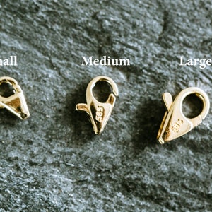 May include: Three gold-toned lobster clasps in different sizes: small, medium, and large. Each clasp has a spring-loaded mechanism and a secure closure.