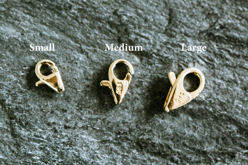 May include: Three gold-toned lobster clasps in different sizes: small, medium, and large. Each clasp has a spring-loaded mechanism and a secure closure.