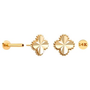 May include: Gold-colored jewelry set featuring a clover-shaped stud earring, a flat-backed stud, and a small round charm with "14K" text. The clover earrings have a faceted design and are surrounded by small beaded accents.