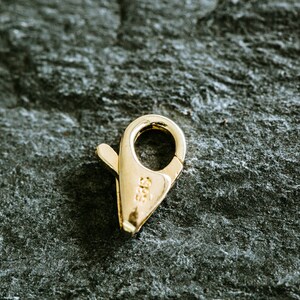 May include: A gold-toned metal clasp with a spring-loaded closure. The clasp is marked with "585", indicating it is made of 14 karat gold.