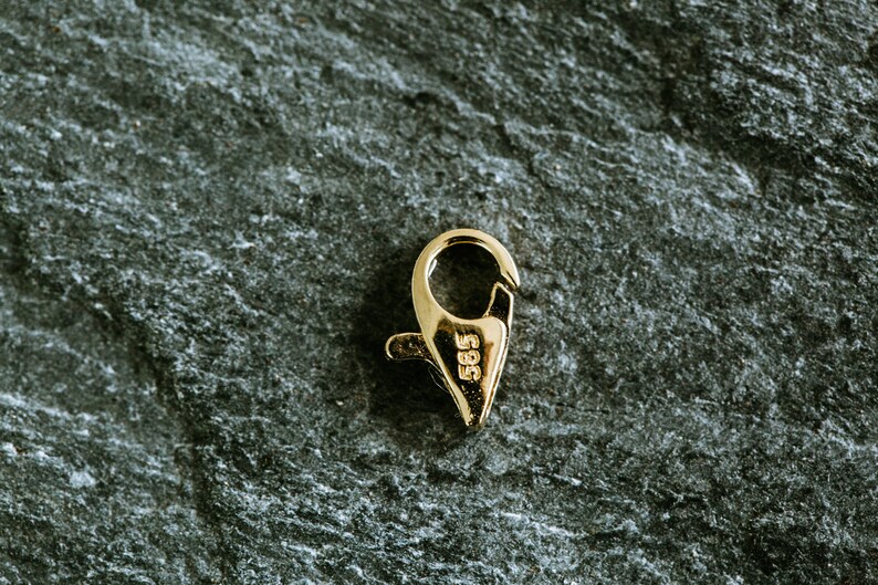 May include: Gold-toned metal clasp with a spring-loaded closure. The clasp is marked with the number "585".