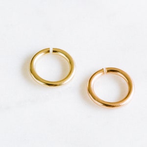 Peut inclure: Deux anneaux de saut en or, l'un en or brillant et l'autre en or rose. Les anneaux sont ouverts et pr&ecirc;ts &agrave; &ecirc;tre utilis&eacute;s pour la fabrication de bijoux.