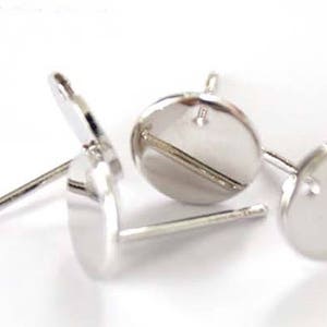May include: Three silver earring blanks with a round, flat base and a post for attaching earrings. The blanks are designed for crafting and customizing.