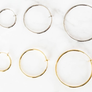 May include: Five pairs of hoop earrings in different sizes. Two pairs are silver and three pairs are gold.