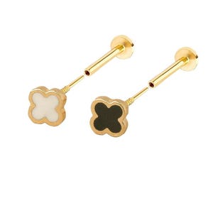 May include: Two gold-toned earrings with a four-leaf clover design. One earring has a white center and the other has a black center.