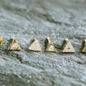 Puede incluir: Seis pendientes de triángulo de oro con diferentes diseños. Algunos pendientes están engastados con pequeños diamantes, mientras que otros son de oro liso.