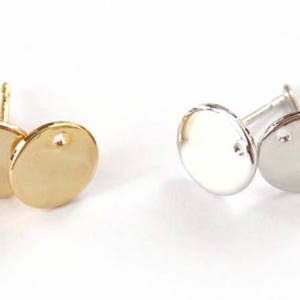 May include: Two pairs of round earring blanks, one pair is gold and the other is silver.