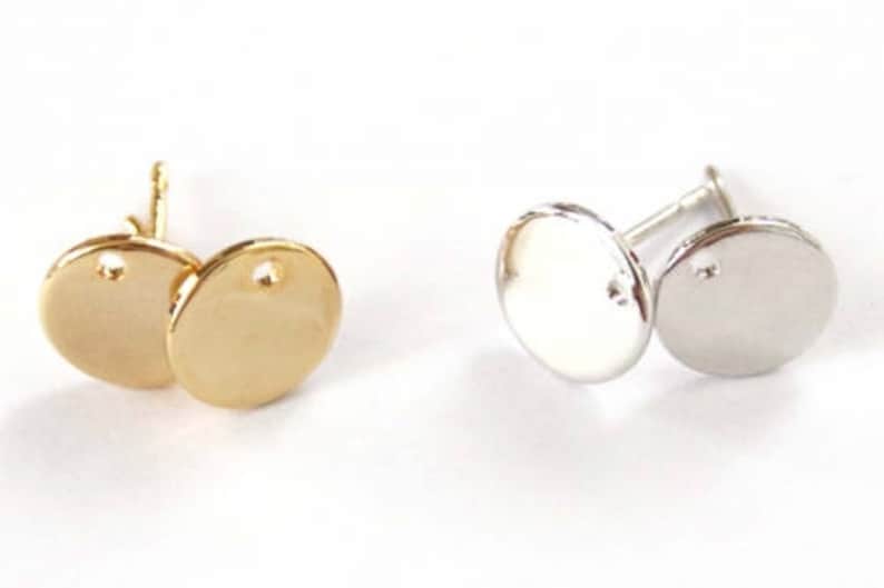 May include: Two pairs of round earring blanks, one pair is gold and the other is silver.
