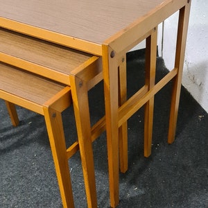 Pode incluir: Um conjunto de três mesas de encaixe de madeira com acabamento marrom claro. As mesas são feitas de madeira maciça e têm um design simples e moderno.