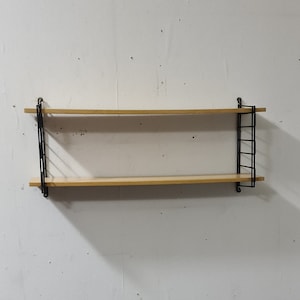 May include: A two-tiered wooden shelf unit with black metal supports. The shelf is mounted on a white wall.