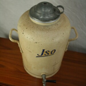 May include: A vintage, cream-colored metal water dispenser with a silver lid and a blue and yellow "Jso" logo. The dispenser has two handles and a spigot.