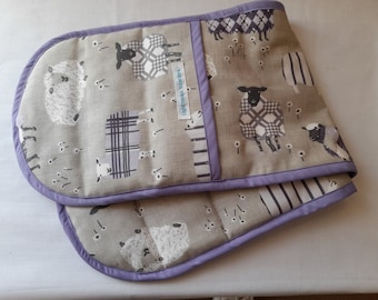 A stylish  padded double handed oven glove in a lovely country design of sheep in mauve and cream on a stone background.
