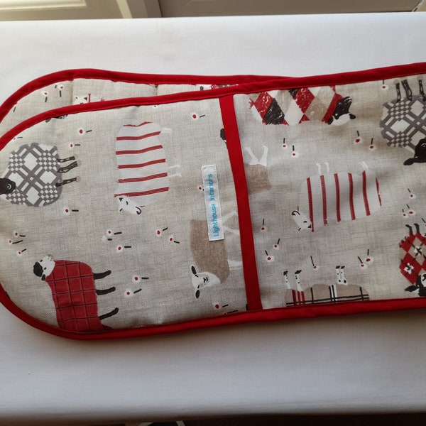 A stylish  padded double handed oven glove in a lovely country design of sheep in red and cream on a stone background.