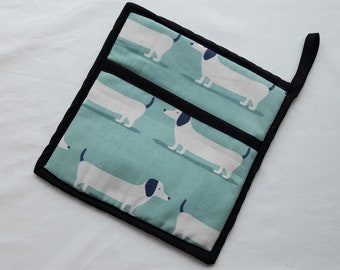 Pot holder in a blue dachshund design, padded in heat resistant wadding and trimmed in black cotton binding.