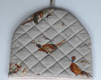 A stylish padded tea cosy in organic cotton in a pheasant design, lined in white cotton and trimmed with  cream tape.