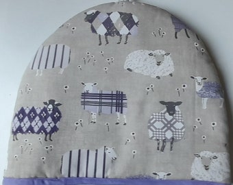 A stylish padded tea cosy in organic cotton in a mauve comedy sheep design lined in white cotton and trimmed in mauve binding.