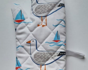 Quilted padded oven glove / oven mitt / pot holder in organic cotton in whitby seagull  design  on white background.
